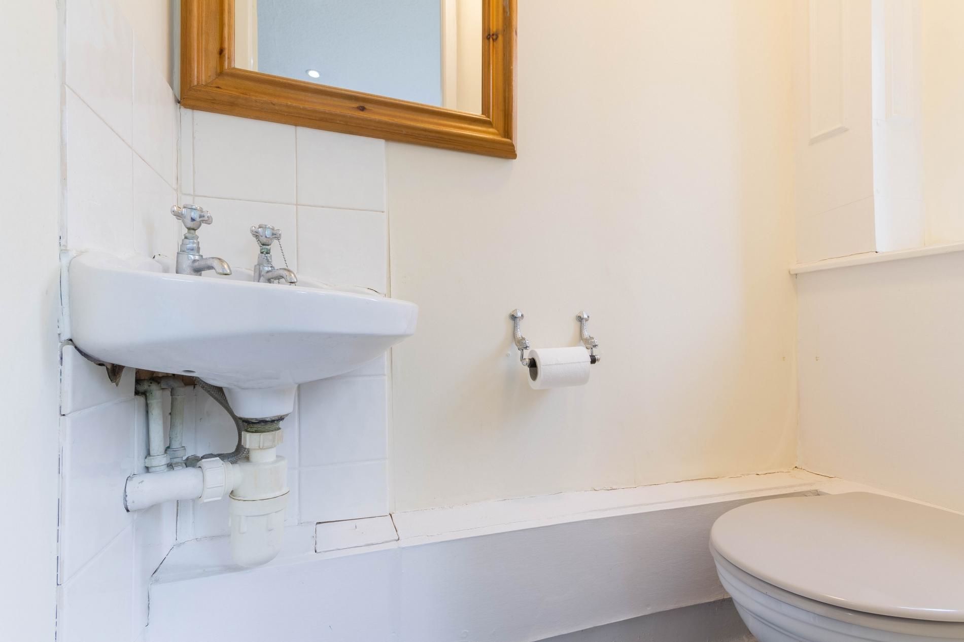 A bathroom with a white sink, a toilet, and a mirror with a wooden frame.