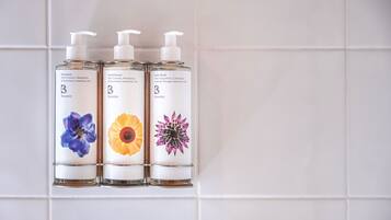 Tre flaconi di bagnoschiuma e balsamo Bramley con diverse illustrazioni floreali.