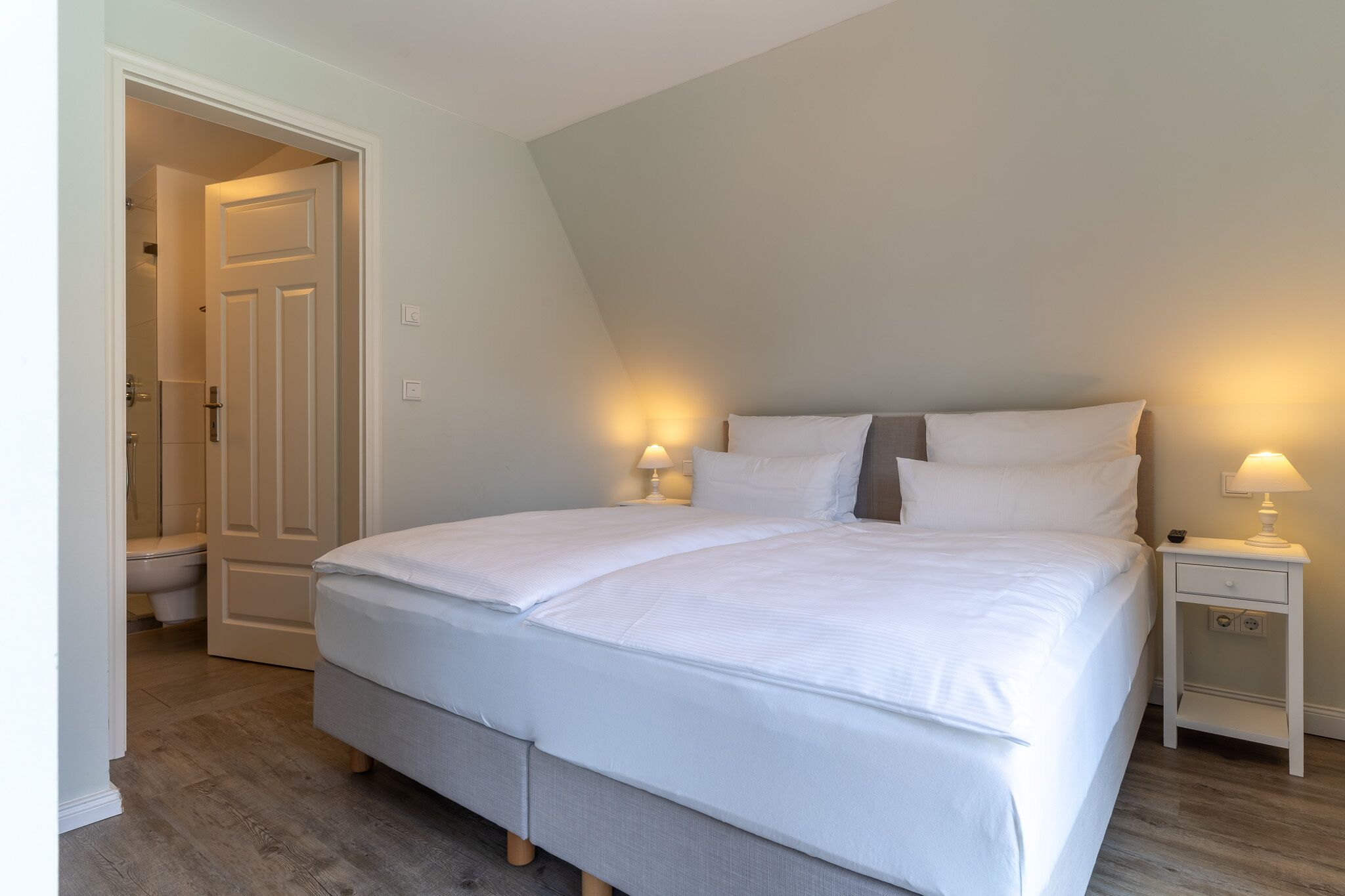 Ein Schlafzimmer mit einem Bett, Nachttischen und einer Tür zu einem Badezimmer.