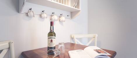 Ein Holztisch mit einer Jameson Whiskey-Flasche, einem Glas und einem offenen Buch.