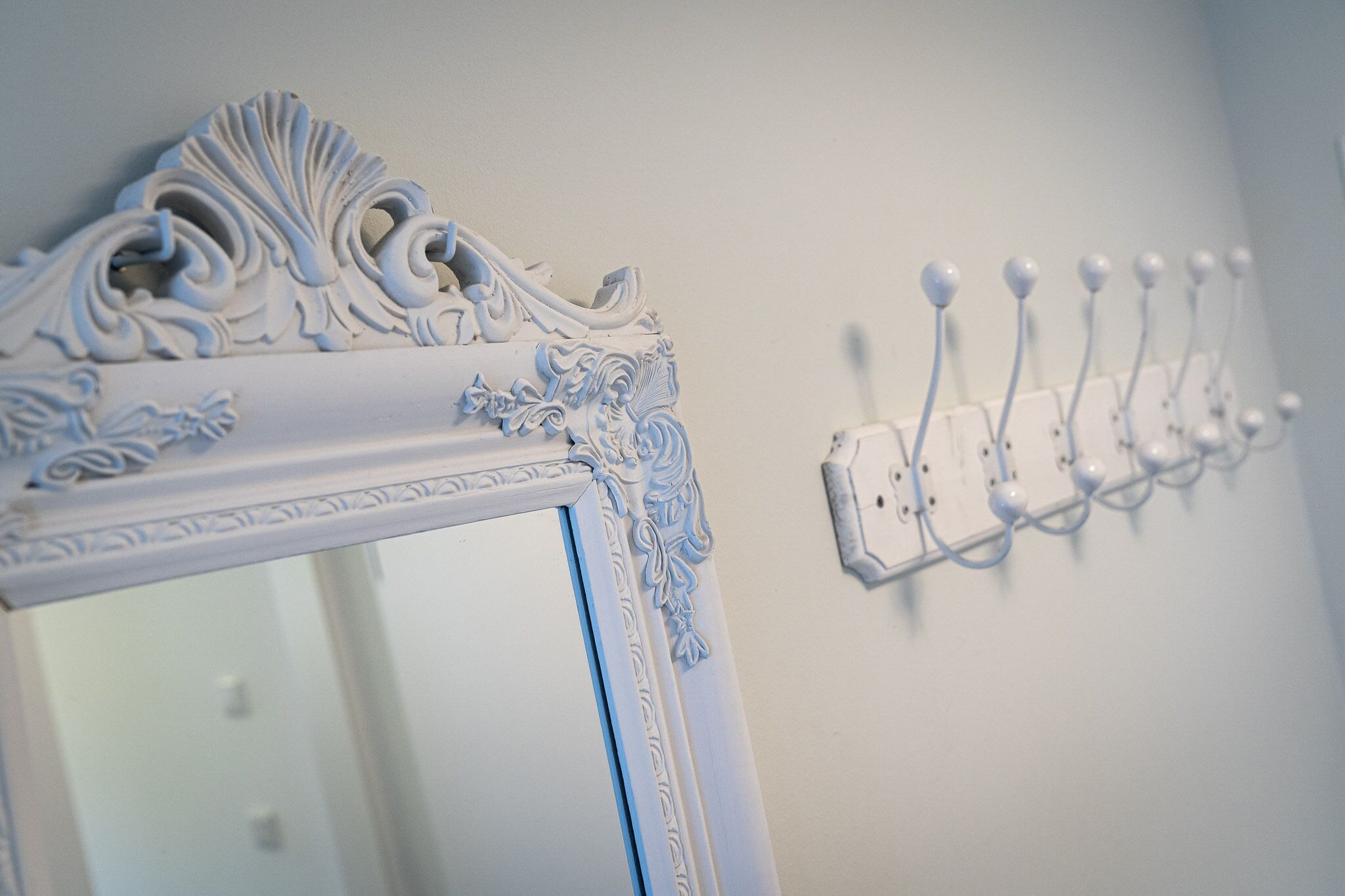 A mirror with ornate carvings and a wall-mounted light switch.