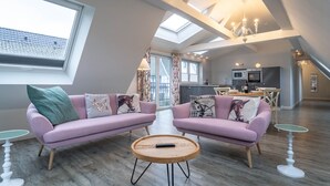A modern living room with two pink sofas, a wooden coffee table, and a large skylight. - Hotel Tweed (St. Peter-Ording)