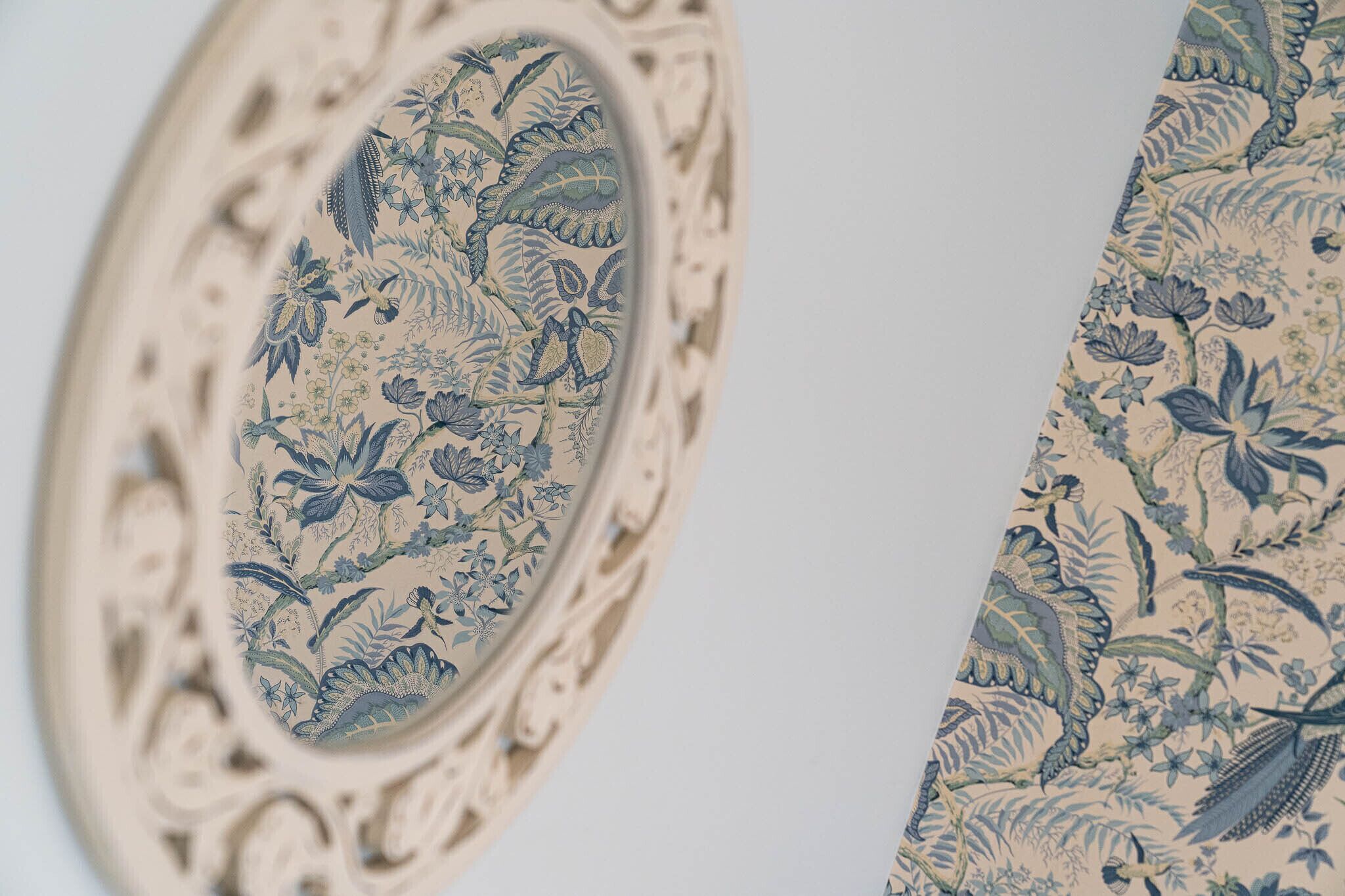 Primer plano de un espejo decorativo con un marco ornamentado y un diseño floral.