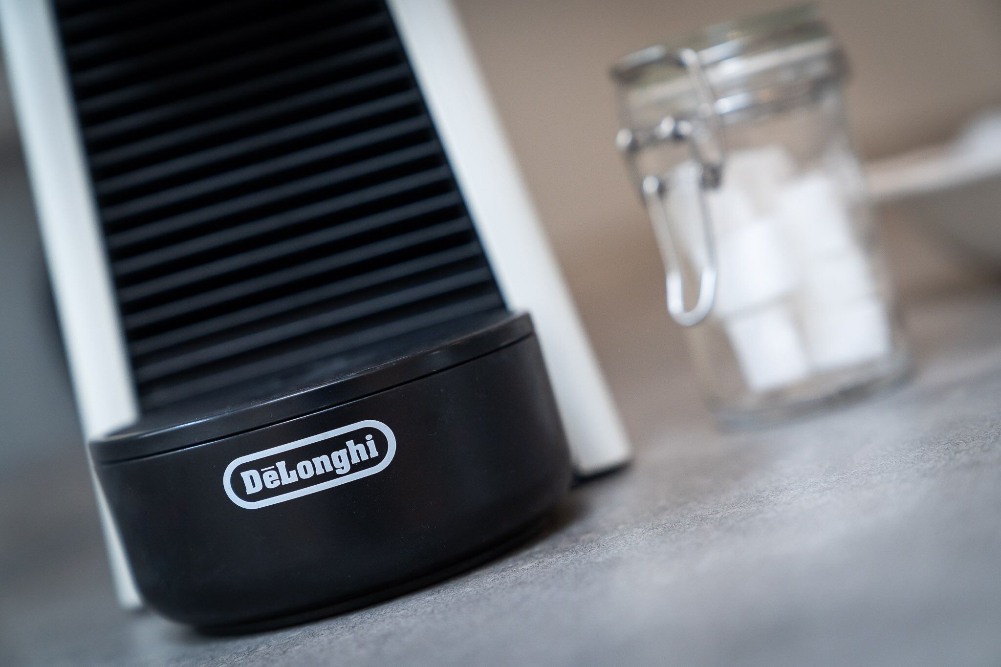 Un appareil DeLonghi, peut-être une machine à café, est posé sur un plan de travail, à côté d’un bocal en verre.