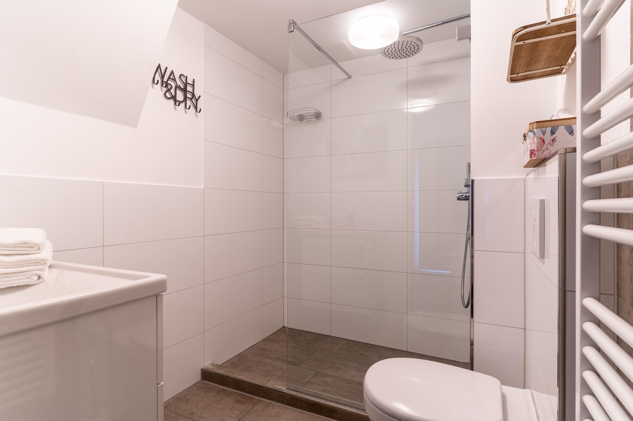 Une salle de bain moderne dotée d’une douche à parois de verre, de toilettes et d’un lavabo.