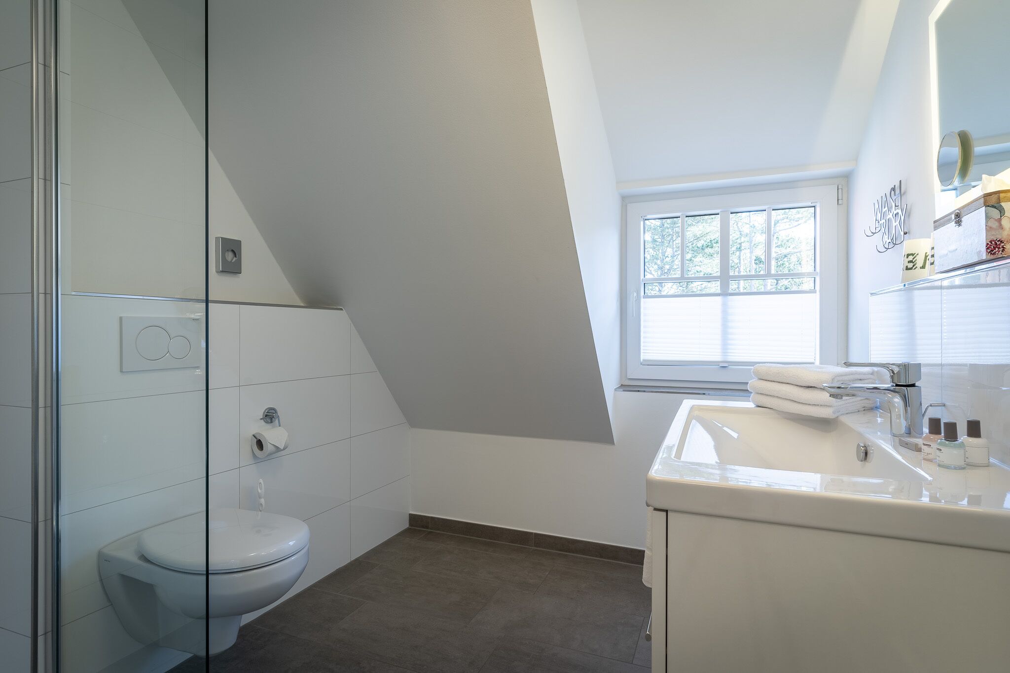 A modern bathroom with a toilet, sink, and shower area.
