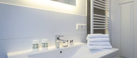 A modern bathroom with a white sink, mirror, and towel rack.