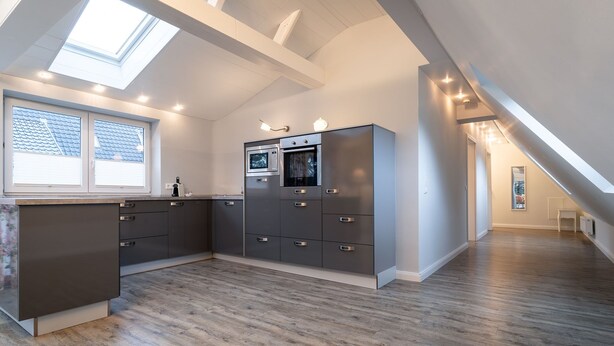 A modern kitchen with a skylight, built-in appliances, and a wooden floor. - Hotel Tweed (St. Peter-Ording)