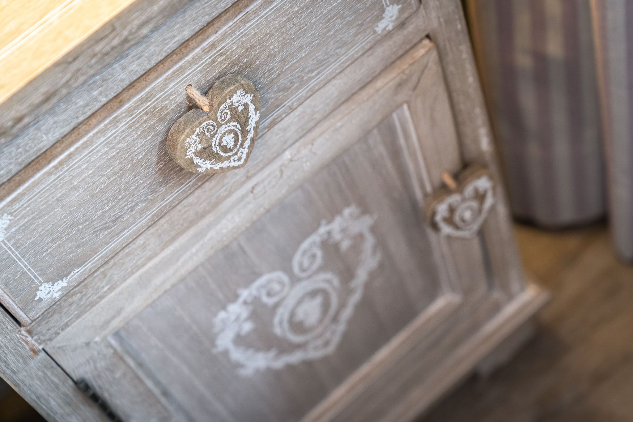 Une commode en bois ornée d’une poignée en forme de cœur et de motifs sculptés.