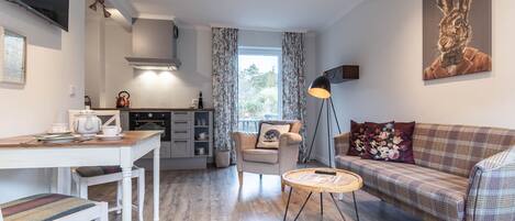 A modern living room with a sofa, a coffee table, and a dining area with a table and chairs.