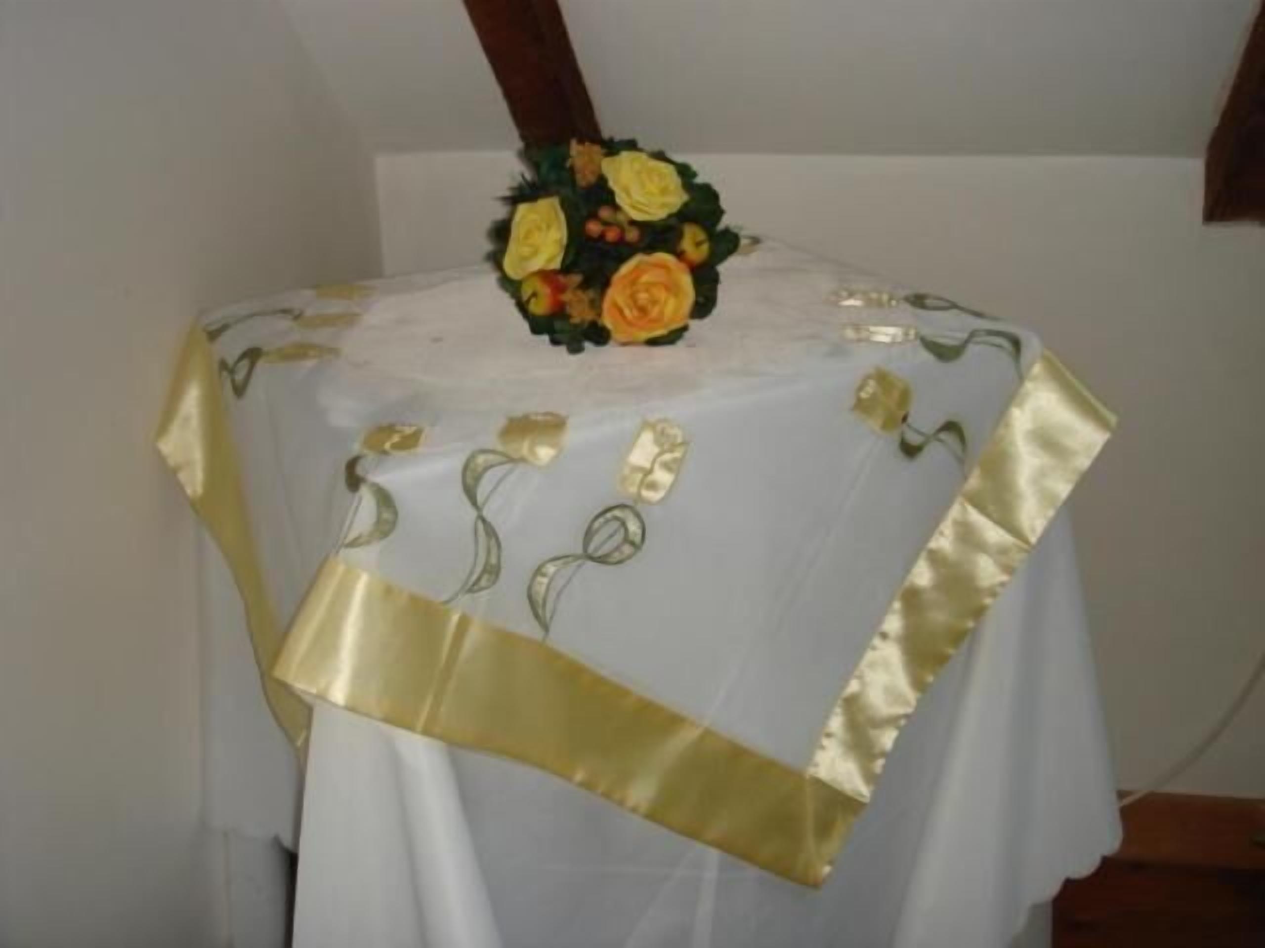 A table with a white tablecloth and gold trim, featuring embroidered designs.