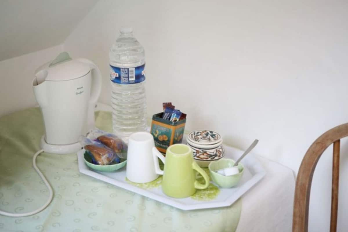 A small kitchenette area with a kettle, a water bottle, a mug, a bowl, and a tray with food items.