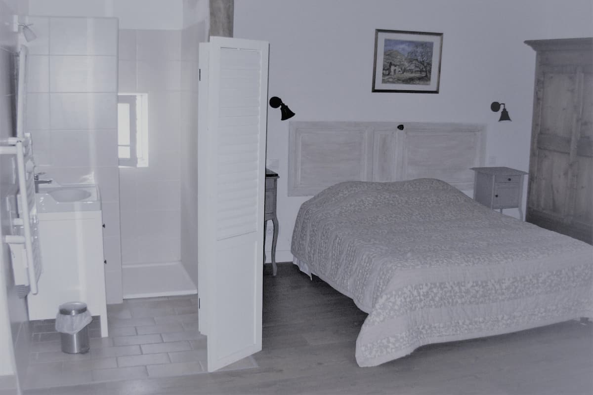 Un dormitorio con cama, mesita de noche, cómoda y ventana.