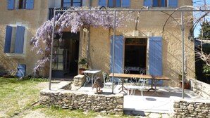 A rustic building with a balcony, stone walls, and a table with chairs. - Mas Las Vitalis (L'Isle-sur-la-Sorgue)