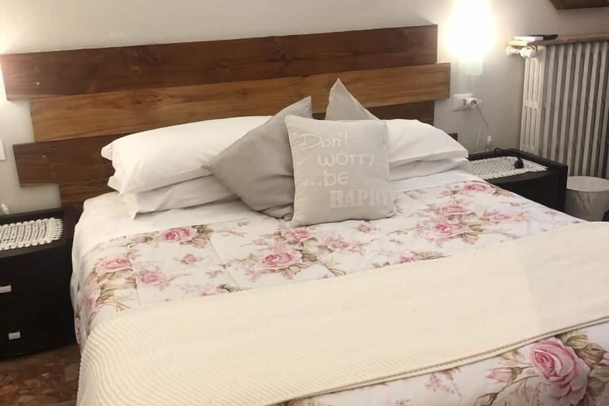 A neatly made bed with floral bedding and a pillow with a motivational quote.