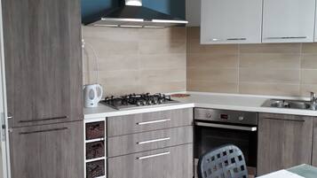 A kitchen with a gas stove, white cabinets, a blue wall, and a dining area with a table and chairs.