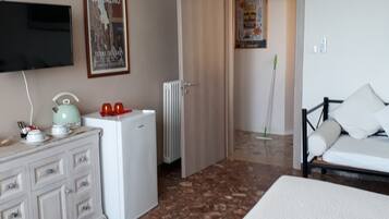 Ein Hotelzimmer mit Bett, Kommode, Heizkörper, Fernseher und einer grünen Deckenleuchte.