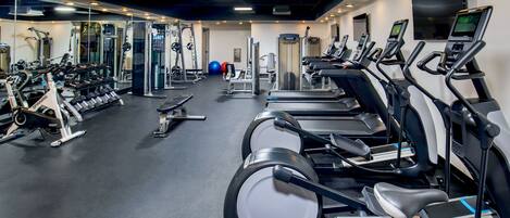 A gym with multiple treadmills, weight machines, and free weights.
