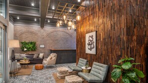 Un espace de détente moderne avec un mur en briques, un lambris en bois et différents types de sièges, notamment un canapé, des fauteuils et des poufs.
