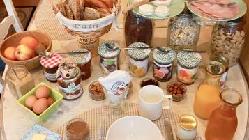Een ontbijttafel met diverse soorten eten, zoals brood, kaas, fruit en drankjes.