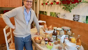 A breakfast table with various food items and a person standing beside it. - NATURALBNB (Villeurbanne)