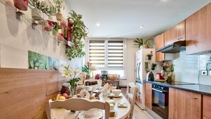 A kitchen with wooden cabinets, a dining table set for four, and various kitchen appliances. - NATURALBNB (Villeurbanne)