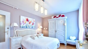 A bedroom with a white bed, bedside tables, a wardrobe, and a painting on the wall. - NATURALBNB (Villeurbanne)
