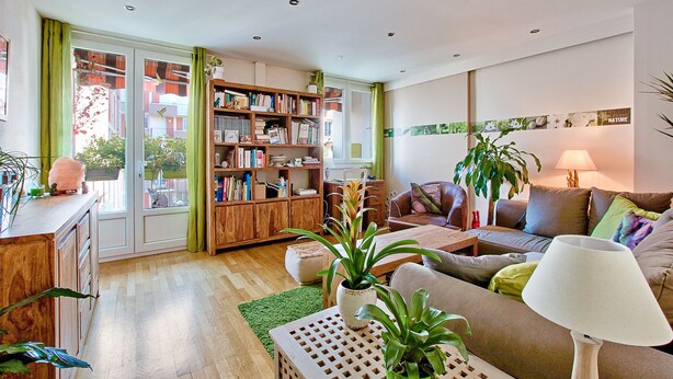 A living room with a wooden bookshelf, a sofa, a coffee table, and a lamp. - NATURALBNB (Villeurbanne)