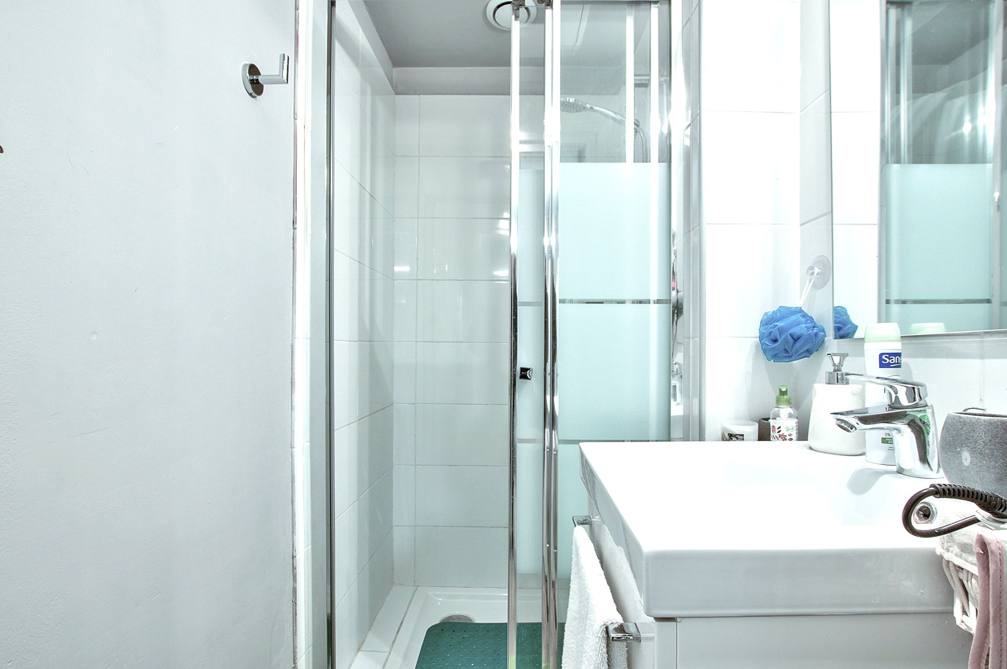 Ein Badezimmer mit Glasdusche, einem weißen Waschbecken und einem Spiegel.
