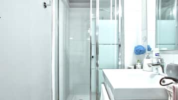 Ein Badezimmer mit Glasdusche, einem weißen Waschbecken und einem Spiegel.