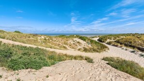 A sandy beach with dunes and a clear blue sky. - Zeegerucht Duplex (Koksijde)