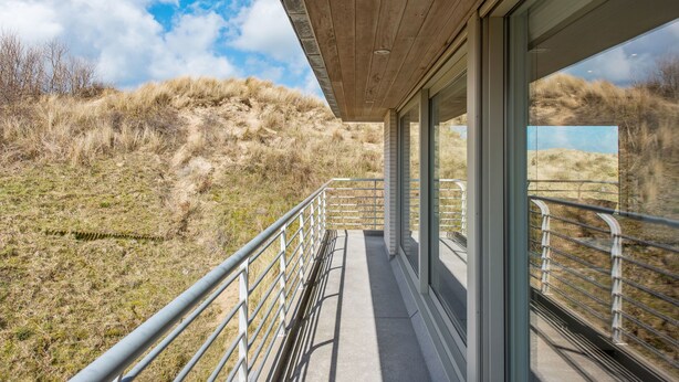 A modern building with a wooden ceiling and large windows overlooking a grassy landscape. - Zeegerucht Duplex (Koksijde)