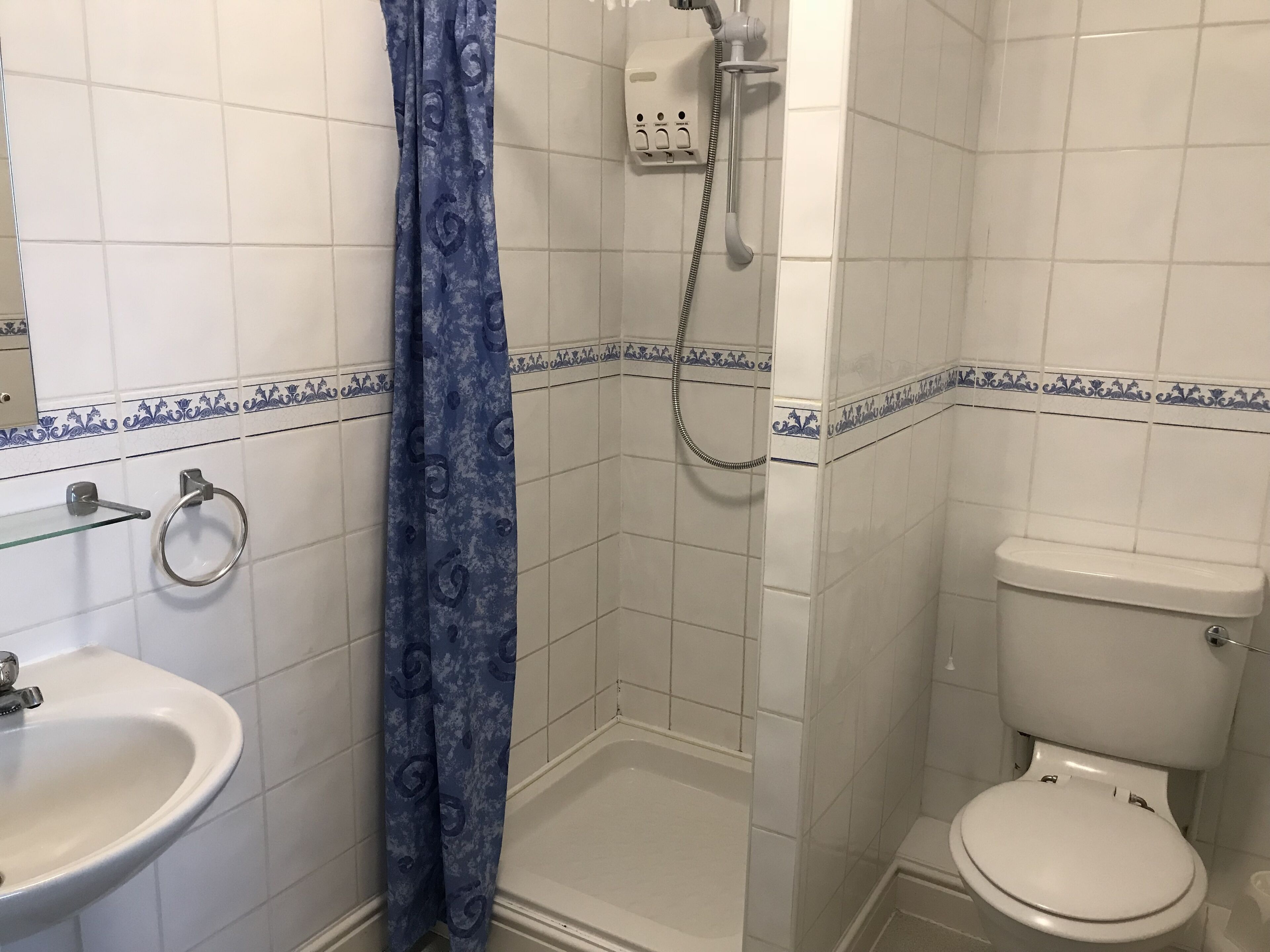 A bathroom with a shower, toilet, and sink.
