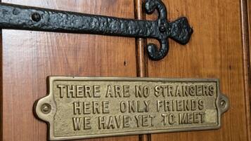 A wooden door with a metal plaque that reads "THERE ARE NO STRANGERS HERE ONLY FRIENDS WE HAVE YET TO MEET."