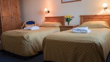 Ein Hotelzimmer mit zwei Betten, Holz-Kopfteilen, einem Holzschrank und einem gerahmten Bild an der Wand.