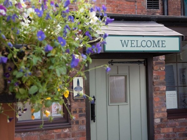 A brick building with a green awning displaying the word "WELCOME".