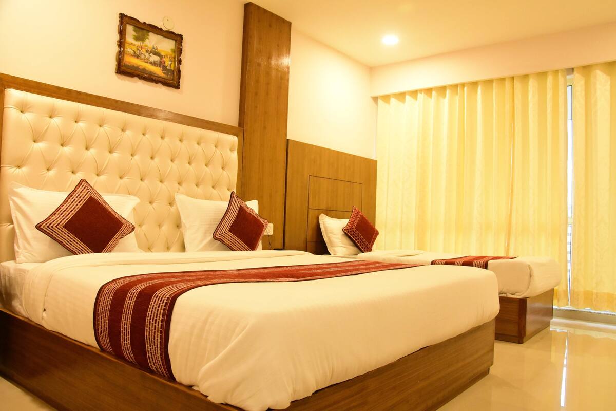A large bed with a tufted headboard, white bedding, and red accents.
