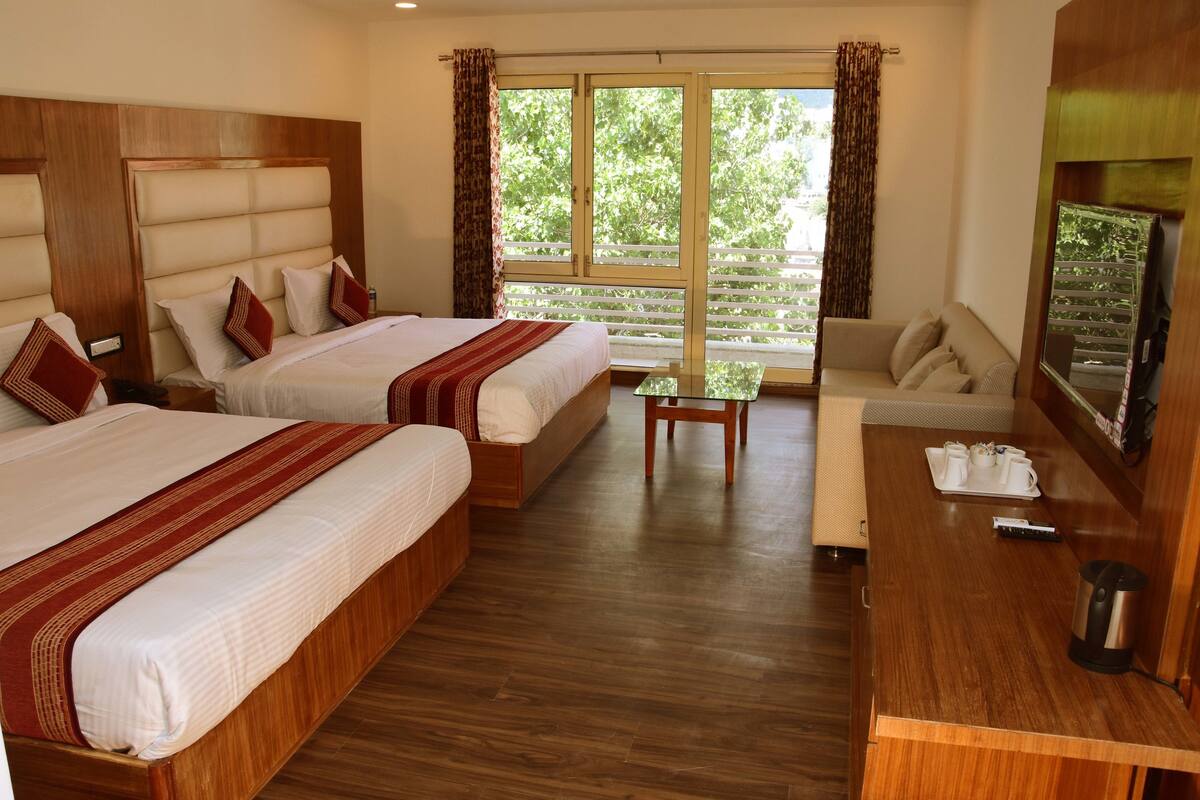 A hotel room with two beds, a sofa, a table, and a TV.