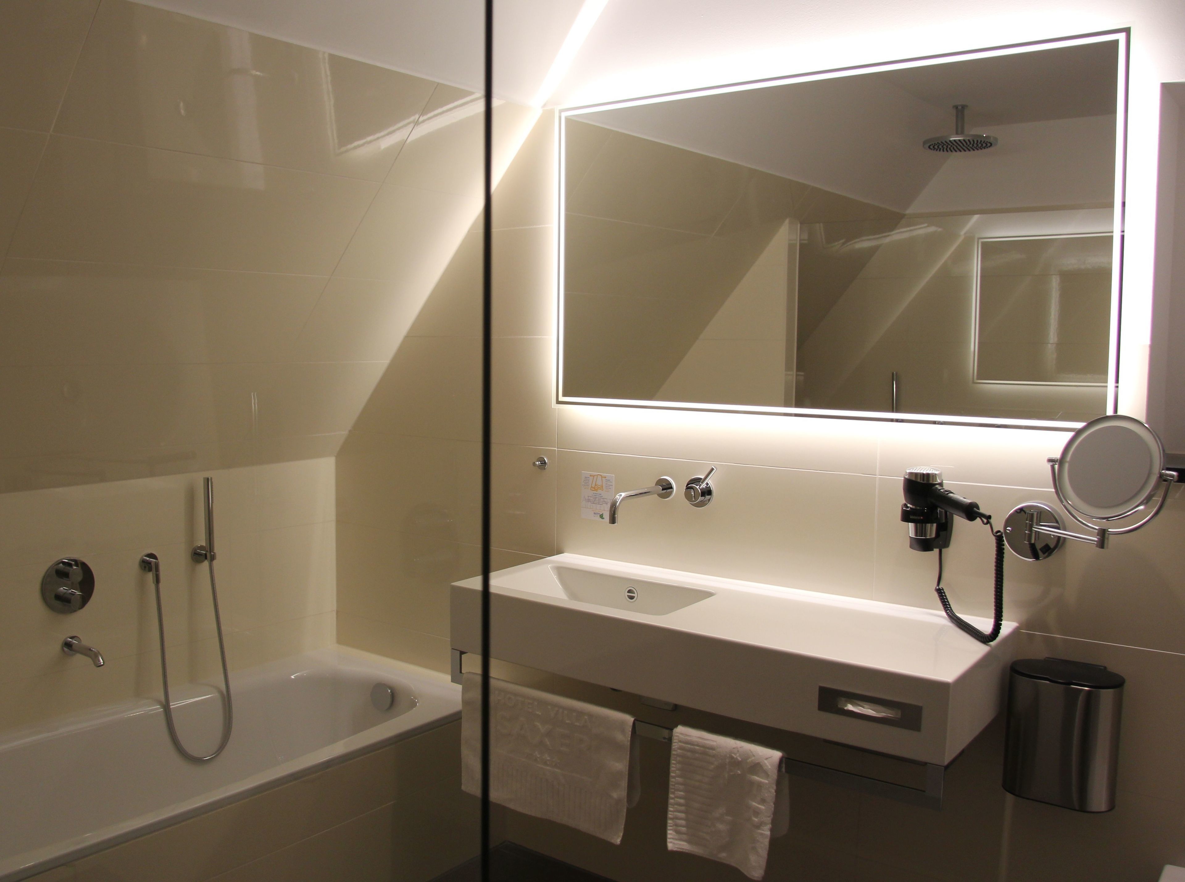 Un baño moderno con bañera, ducha, lavabo y espejo.