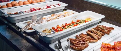 Un bufé con diversas opciones de comida, como huevos, verduras y salchichas.