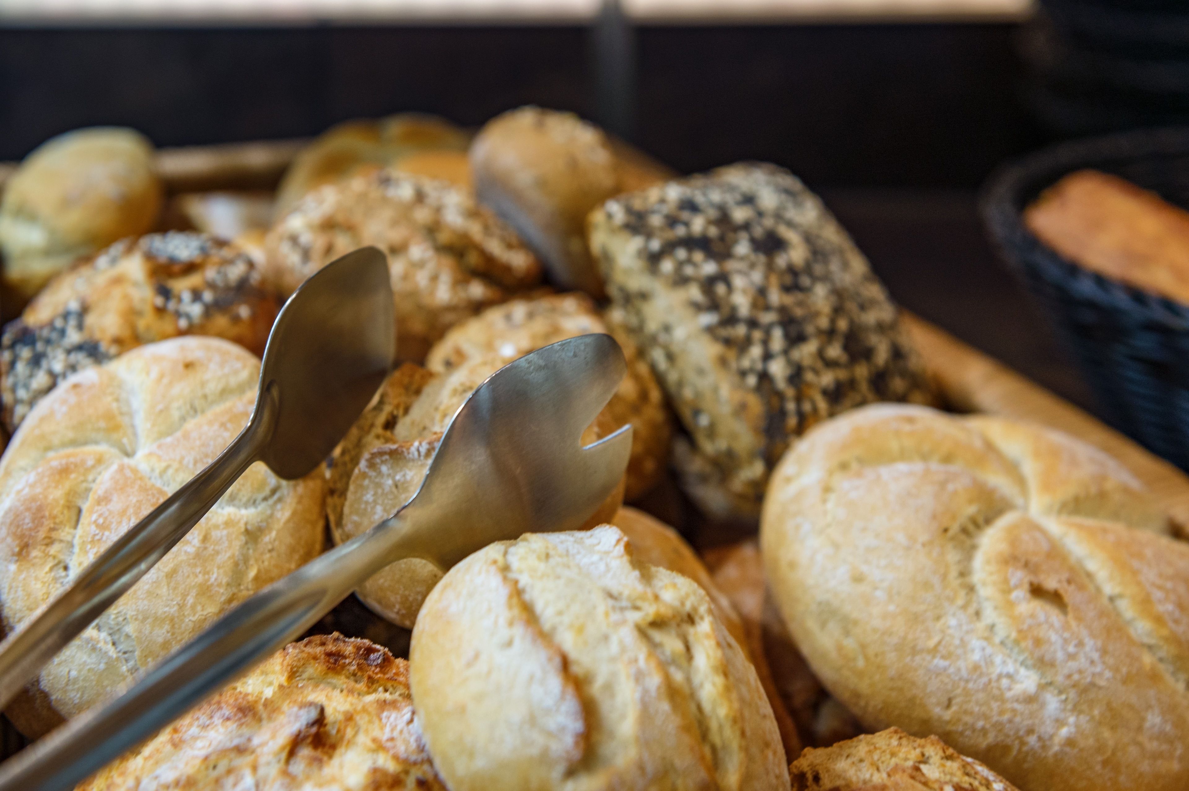 A variety of breads and rolls, including some with seeds and others with a crusty exterior.