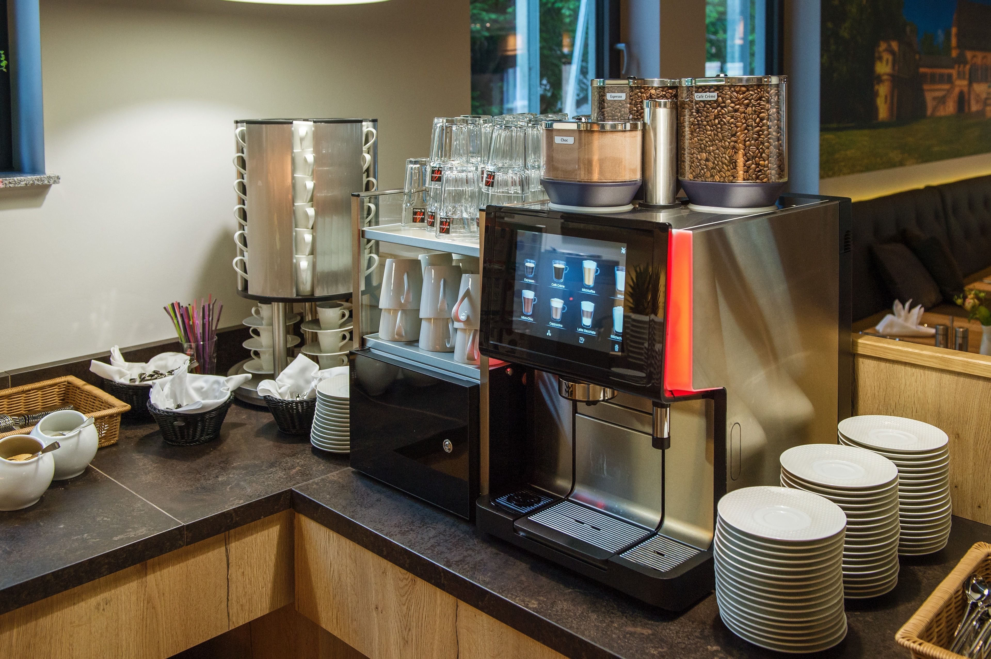 A coffee station with a coffee machine, cups, and a coffee bean dispenser.