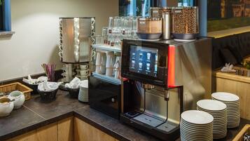 A coffee station with a coffee machine, cups, and a coffee bean dispenser.