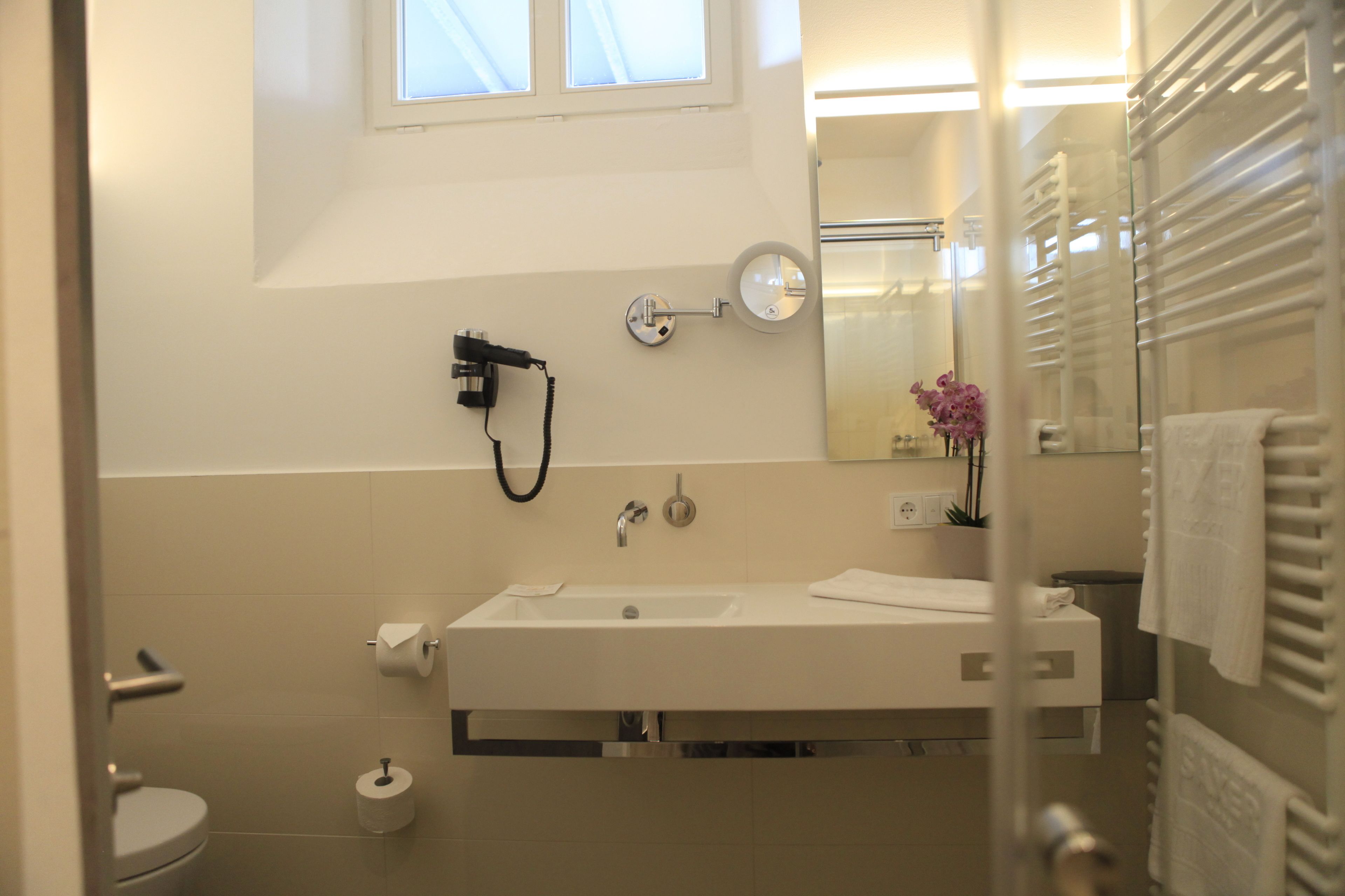 A modern bathroom with a white sink, mirror, and towel rack.