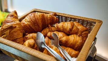 A wicker basket filled with croissants and two metal spoons.