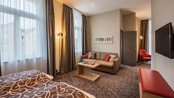 Ein Hotelzimmer mit einem Bett, einer Couch, einem kleinen Tisch und einem Fernseher.