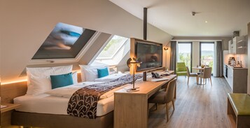 Ein modernes Hotelzimmer mit Bett, Schreibtisch, Fernseher und einem Balkon mit Aussicht.