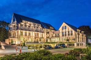 A large, multi-story hotel with a modern design, featuring balconies, a covered parking area, and lush landscaping. - AKZENT Hotel Villa Saxer (Goslar)