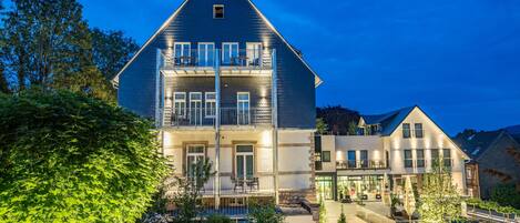 Ein zweistöckiges Gebäude mit Balkon, Garten und Kiesweg.