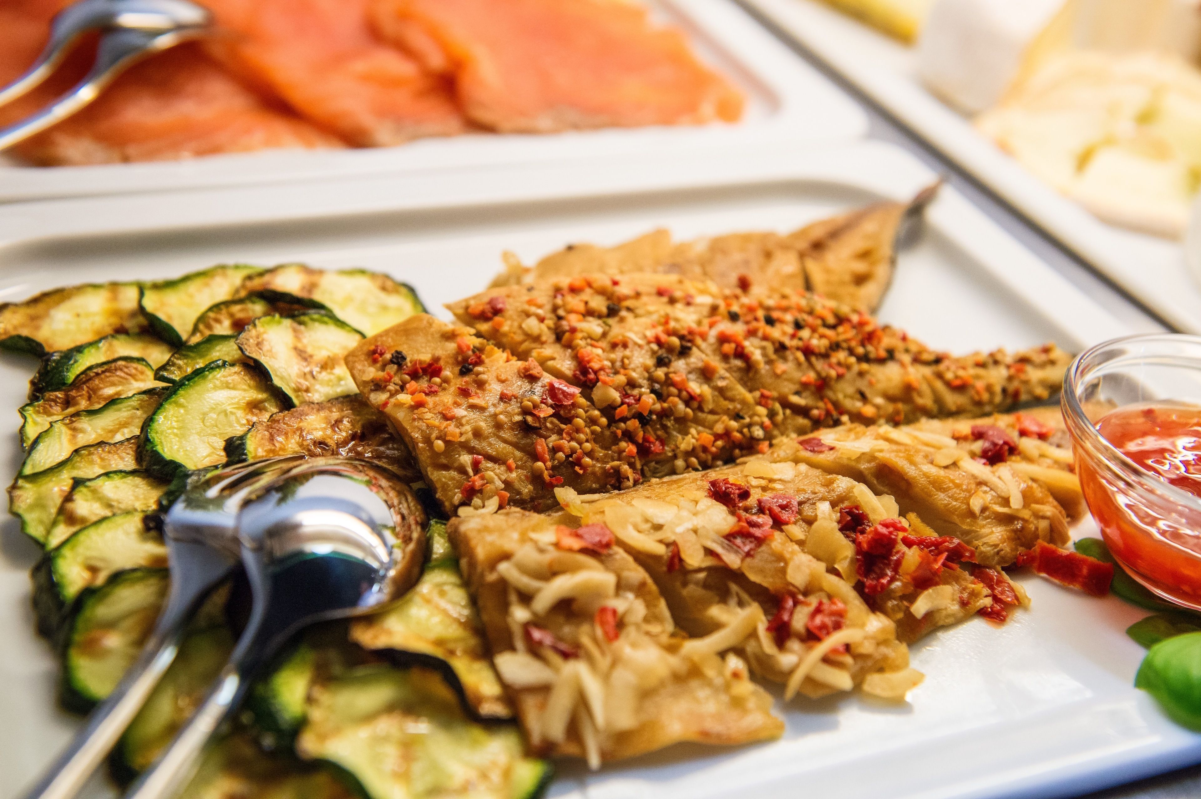 Un buffet proposant des légumes grillés, du tofu et du saumon.
